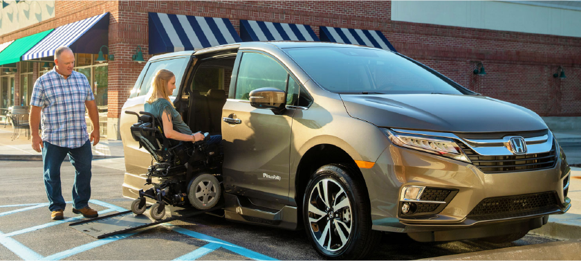 Person helping her wheelchair-bound partner into a handicap van.